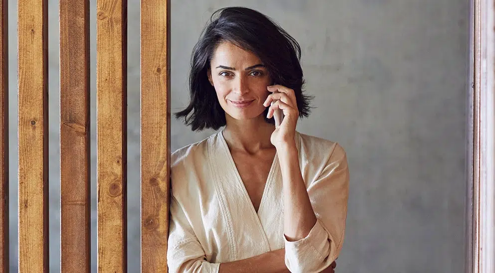 Telefonierende Frau neben einer Holzwand, BFS finance GmbH