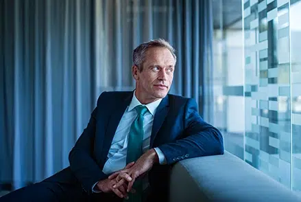 Mann schaut aus dem Fenster, blauer Hintergrund, BFS finance