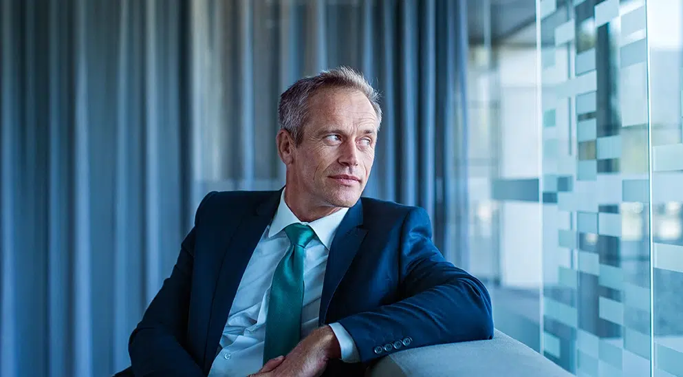 Mann schaut aus dem Fenster, blauer Hintergrund, BFS finance